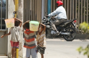 Labarik sira hiit hela has budu iha toples laran ba faan iha dalan publiku. Foto:INDEPENDENTE.